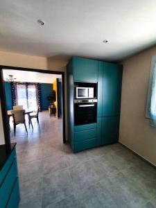 cocina con armarios azules y sala de estar con mesa en Villa Mon Caprice en Roquemaure