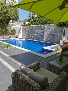 a swimming pool with an umbrella and chairs and a table at Villa de Charme Adultes Only in Nabeul