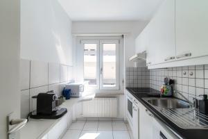 eine weiße Küche mit einem Waschbecken und einem Fenster in der Unterkunft Victoria Apartment by Quokka 360 - simple and practical flat in Locarno in Solduno