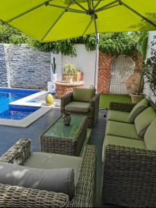 patio z krzesłami i parasolem przy basenie w obiekcie Villa de Charme Adultes Only w mieście Nabul