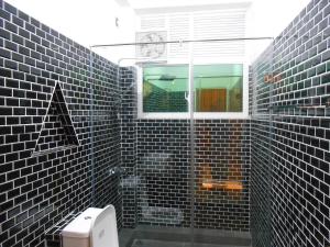 a bathroom with black tiled walls and a toilet at Luxury apartment The Walkers Nest in Kandy