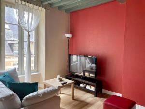 salon z czerwoną ścianą i telewizorem w obiekcie Le Liberty by Melrose w mieście Bayeux