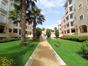 ein Innenhof mit Palmen und Bänken in einem Gebäude in der Unterkunft PRECIOSOS APARTAMENTO DE DOS DORMITORIOS in Ayamonte