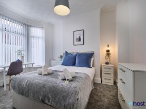 a bedroom with a bed with blue pillows and a desk at Host Liverpool - Smithdown Hub, Shops & Eats, by centre in Liverpool