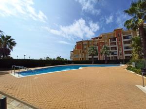 ein Schwimmbad vor einem Gebäude in der Unterkunft PRECIOSOS APARTAMENTO DE DOS DORMITORIOS in Ayamonte