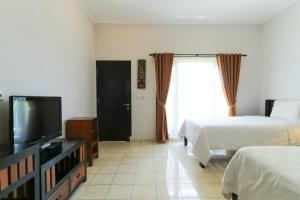 a hotel room with two beds and a flat screen tv at Puri Hasu Bali in Jimbaran