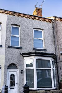 een grijs huis met witte ramen en een deur bij Warwick West in Barrow in Furness