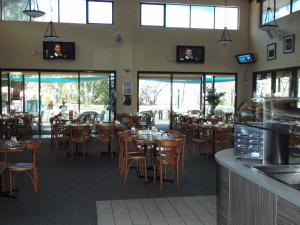 a restaurant with wooden tables and chairs and windows at Bushland Beach Tavern in Townsville