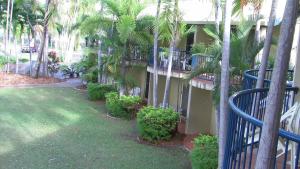 a building with palm trees next to a yard at Bushland Beach Tavern in Townsville