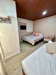 a bedroom with two beds and a couch and a tv at Pousada Rota do Sol Quarto Filial Rose 11 in Penha