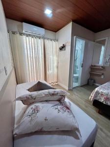 a bedroom with a bed and two pillows on it at Pousada Rota do Sol Quarto Filial Rose 11 in Penha