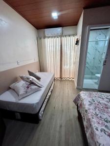 a small room with two beds and a window at Pousada Rota do Sol Quarto Filial Rose 11 in Penha