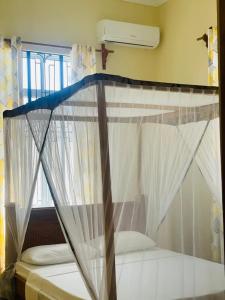 a bed with a canopy in a room at Mbuyu Uvi Apartment in Paje