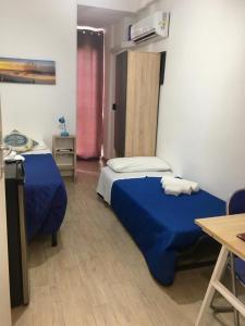 1 dormitorio con 2 camas con sábanas azules y mesa en Casa di Angela en Sciacca