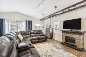 a living room with a leather couch and a fireplace at Modern Cambridge Cottage Walk to Town, Waterfront in Cambridge