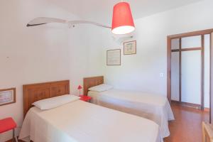 two beds in a room with white walls at Villetta Schiopparello by HelloElba in Portoferraio
