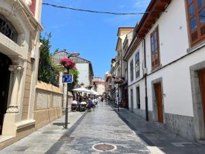 a street in an old town with people sitting on chairs at Aramar Luanco in Luanco