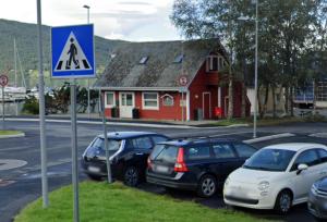 eine Gruppe von Autos, die vor einem roten Haus geparkt sind in der Unterkunft Skålafjæro 25 in Rosendal