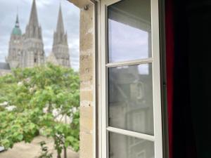 otwarte okno z widokiem na budynek w obiekcie Le Liberty by Melrose w mieście Bayeux