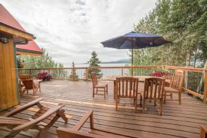 una terraza de madera con mesa, sillas y sombrilla en Inn on the Lake - Whitehorse en Marsh Lake