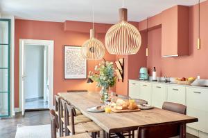 uma cozinha com paredes cor de laranja e uma mesa e cadeiras de madeira em Large 4 bedroom with Balcony & Bathtub in CPH City em Copenhague