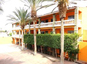 an orange building with palm trees in front of it at Hotel La Hacienda de la Langosta Roja in San Felipe