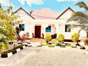 biały dom z palmą w obiekcie Mbuyu Uvi Apartment w mieście Paje