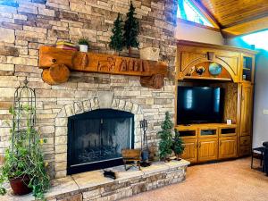 a living room with a stone fireplace with a tv at Charming School House with Large Pool in Huron