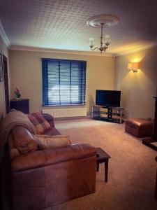 sala de estar con sofá y TV de pantalla plana en Home away from home, en Workington