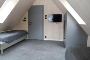 1 dormitorio con 1 cama y TV en la pared en Chata Jestřábník en Dolní Morava
