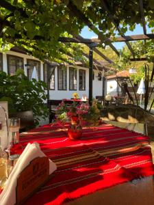 a table with a red table cloth with flowers on it at Хотел механа Караджейката in Gradets +13 photos
