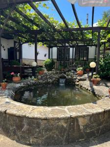 a pond in a garden with a pergola at Хотел механа Караджейката 