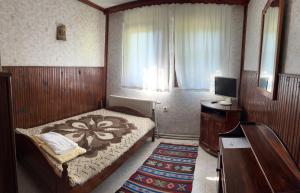 a bedroom with a bed and a desk and a television at Хотел механа Караджейката 
