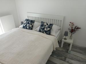 ein Schlafzimmer mit einem weißen Bett mit blauen und weißen Kissen in der Unterkunft HANDLER Apartman Sopron in Sopron