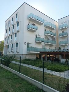 ein weißes Apartmenthaus mit einem Zaun davor in der Unterkunft HANDLER Apartman Sopron in Sopron