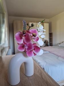 eine weiße Vase mit rosa und weißen Blumen auf dem Bett in der Unterkunft Orange house Šempeter in Šempeter v Savinjski Dolini