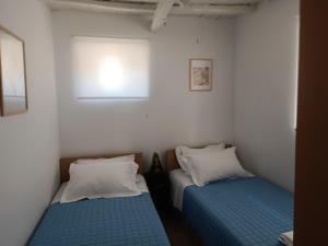 two beds in a small room with white walls at Perseids Traditional House in Amorgos