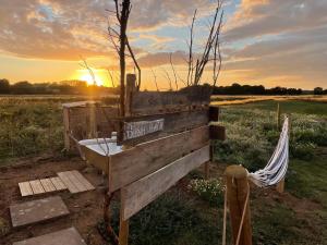 a wooden bench with a bath tub in a field at Bain View Glamping in Horncastle