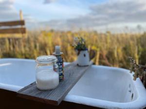 un barattolo di sapone su un vassoio di legno accanto a una vasca da bagno di Bain View Glamping a Horncastle