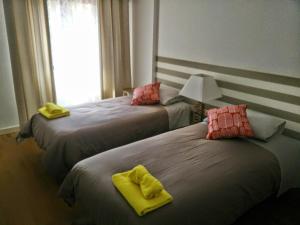 two beds in a room with yellow towels on them at Apartment with private parking next to metro station close to center in Lisbon