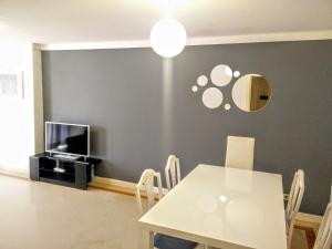 a dining room with a white table and a tv at Apartment with private parking next to metro station close to center in Lisbon