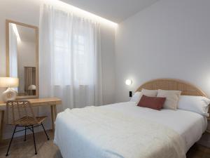a white bedroom with a large bed and a desk at Meraki Suites in Astorga
