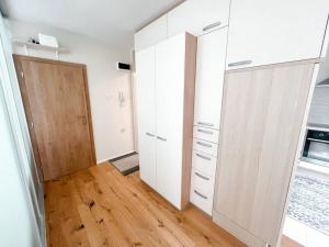 a kitchen with white cabinets and a wooden floor at Apartma Nataša in Jagodje