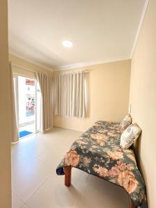 um quarto com uma cama com um edredão floral em Pousada Brilho do Sol em São Miguel do Gostoso
