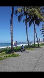 una persona sentada en un banco junto a la playa en Suíte 100m da praia e academia inclusa dias de semana, en Maceió