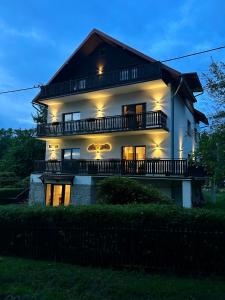 uma grande casa branca com uma varanda à noite em Jeleni Ruczaj em Karpacz