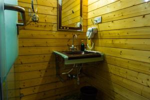 a bathroom with a sink in a wooden wall at The Door to Nirvana Cottages in Coonoor