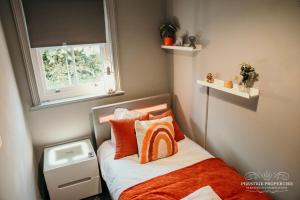 a small bedroom with a bed with orange and white pillows at Princes st by Prestige Properties SA in Ulverston