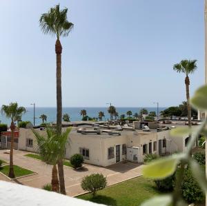 a row of white buildings with palm trees and the ocean at Apartamento PLAYA LAS VENTANICAS in Mojácar