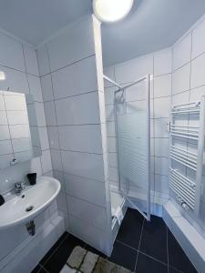a white bathroom with a sink and a shower at Restaurant Donau in Hannover